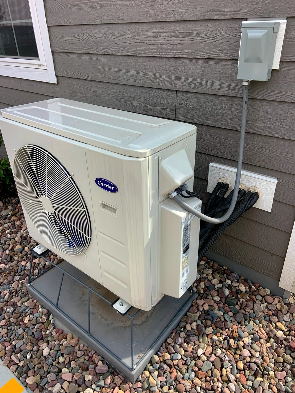 An air-source heat pump outdoor unit beside a house wall